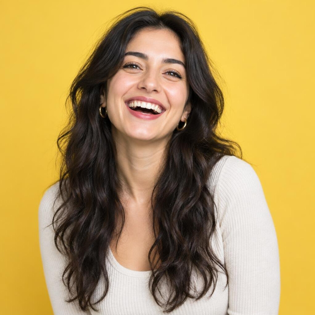 Cheerful young woman with dark curly hair against a warm yellow background